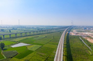 Jingzhou Çin 'deki yeşil tarlalar boyunca uzun bir köprü uzanır..
