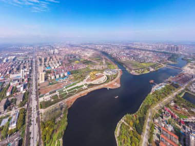 Jingzhou şehri, şehir gelişimini ve doğal su yollarını gösteren açık mavi gökyüzünün altında geniş bir nehir boyunca uzanır..