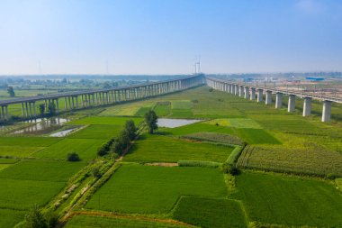 Çin 'in Jingzhou şehrinde geniş bir köprü yeşil tarlalar ve su boyunca uzanır..