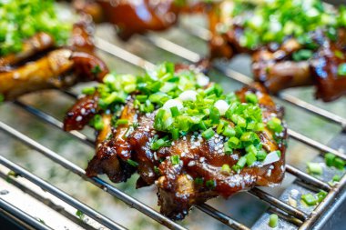 Lezzetli ızgara domuz ayağı, yeşil soğan ve susam tohumlarıyla tatlandırılır..