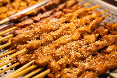 Sıraya dizilmiş susam tohumlu çubuklar üzerindeki etler gösterilir.