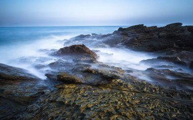 Su Çin 'de deniz kenarındaki kayaların üzerinden akar..