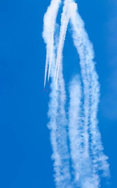 Uçaklar akrobatik manevralar yaparak açık mavi gökyüzüne karşı beyaz duman izleri bırakarak uçuş ve hava gösterilerinin dinamizmini yakalıyorlar..