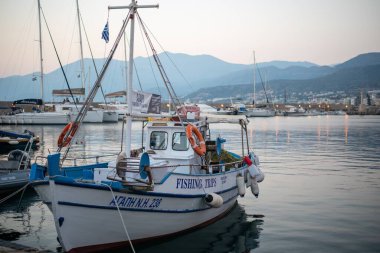 Hersonissos, Girit 'te tekneli bir sahil sahili manzarası. Huzurlu sular, adanın doğal güzelliği tarafından çerçevelenmiş büyüleyici kasabayla buluşur..