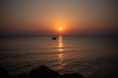 Yunanistan 'ın Girit adasında denizin üzerinde çarpıcı bir gün doğumu. Sakin sular, sabah gökyüzünün altın renklerini yansıtıyor. Huzurlu bir deniz manzarası oluşturuyor..