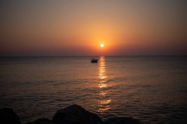 Yunanistan 'ın Girit adasında denizin üzerinde çarpıcı bir gün doğumu. Sakin sular, sabah gökyüzünün altın renklerini yansıtıyor. Huzurlu bir deniz manzarası oluşturuyor..