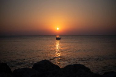 Yunanistan 'ın Girit adasında denizin üzerinde çarpıcı bir gün doğumu. Sakin sular, sabah gökyüzünün altın renklerini yansıtıyor. Huzurlu bir deniz manzarası oluşturuyor..