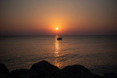 Yunanistan 'ın Girit adasında denizin üzerinde çarpıcı bir gün doğumu. Sakin sular, sabah gökyüzünün altın renklerini yansıtıyor. Huzurlu bir deniz manzarası oluşturuyor..