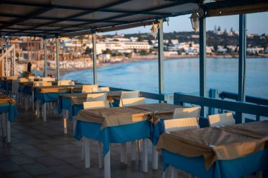 Yunanistan 'ın Girit kentindeki Hersonissos kentindeki büyüleyici bir Yunan restoranında geleneksel dekorasyon ve açık hava koltukları canlı çiçeklerle çevrili..