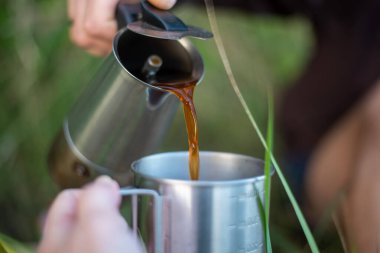 Açık havada kahve hazırlamak, doğa ile çevrili, kamp ve maceranın özünü yakalar, manzaranın ortasında sıcak bir içecek sunar..