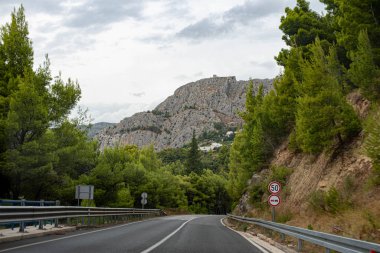 Mountain road in the Dalmatia region, Croatia, winding through scenic landscapes with breathtaking views of the rugged terrain and coastal beauty. A perfect route for road trips. clipart