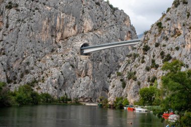Hırvatistan 'daki Cetina Nehri boyunca uzanan Omis köprüsünde manzara tünelleri ve dağ manzaralı bir köprü yer alıyor.