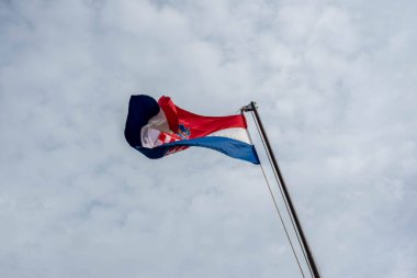 Hırvat bayrağı, ulusal gurur ve vatanseverliği simgeleyen açık mavi gökyüzüne karşı rüzgarda dalgalanıyor.