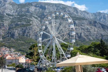 Hırvatistan 'ın Makarska kentinde arka planda dağlar bulunan dönme dolap