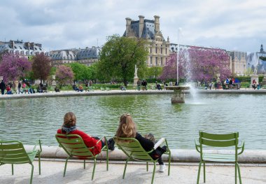 Paris, Fransa - 24 Nisan 2023: Paris 'teki Tuileries Garden çeşmesinin önünde oturan iki genç kız - Jardin des Tuileries Turistleri