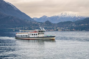 Feribot Como Gölü 'nde karla kaplı bir dağ sırasının arka planına doğru yol alır. Varenna, Lakes Bölgesi, Lombardy, İtalya