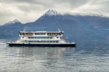 Feribot Como Gölü 'nde karla kaplı bir dağ sırasının arka planına doğru yol alır. Varenna, Lakes Bölgesi, Lombardy, İtalya