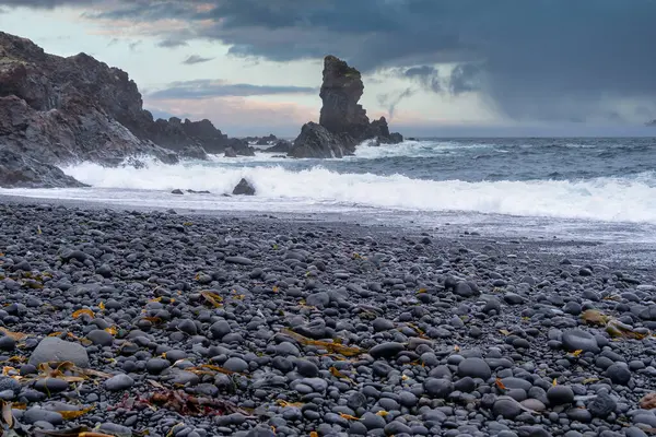 stock image Majestic Black Pebble Beach with Crashing Waves in Iceland  Dramatic Coastal Landscape with Rugged Rock Formations and Stormy Skies, Capturing Nature Untamed Beauty in the North Atlantic