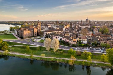 Mantua İtalya 'nın romantik günbatımı manzarası tarihi gökyüzü Castello di San Giorgio nehir kenarı parkı ve demirlemiş tekneler Mincio Nehri manzaralı seyahat manzarasına yansıyor.