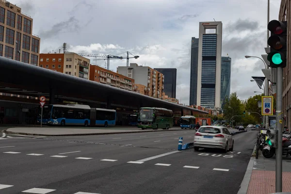 Şehre. Plaza Castilla yolu araçlar, arabalar, motosikletler, otobüsler ve toplu taşıma araçlarıyla dolu, Madrid 'de bulutlu bir günde arka planda gökdelenler var. Zebra geçidinden geçen insanlar.