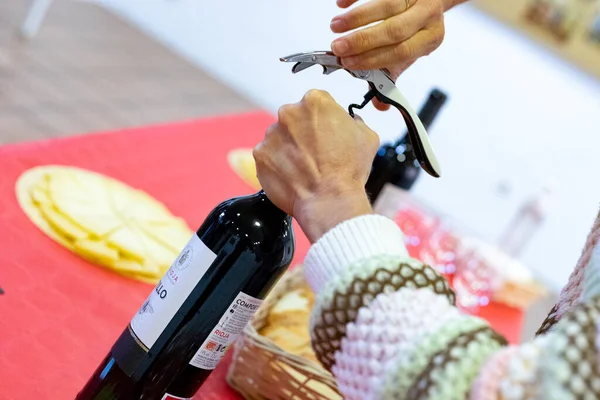 Corkscrew. Came. Time to open the bottle of red wine with the corkscrew. Woman\'s hands holding the bottle while opening the cork. Horizontal photography.