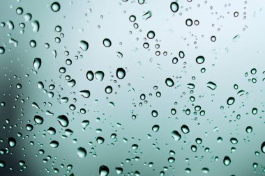 Yağmur. Pencerede yağmur damlaları. Yağmurlu bir gün. Mavi ton. Bardağa bir damla su. Macro vuruldu. Doku. Sonbahar havası kavramı, cam üzerindeki su damlalarının arkaplanı şeffaf..