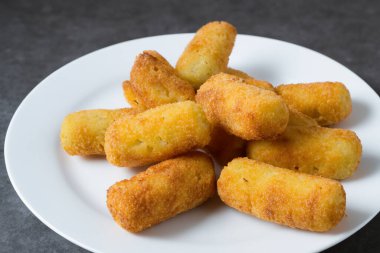 Kroket. Bir tabak kroket. Geleneksel İspanyol ev yapımı kroketler ya da çatallı beyaz tabakta kroketler. Tapas yemeği. Uluslararası Kroket Günü. 16 Ocak. 2024