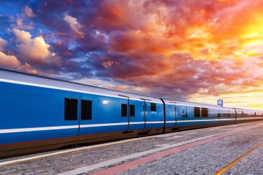 Tren. Modern yüksek hızlı tren istasyon platformunda hareket ediyor. Tren istasyonunun peronunda elektrikli tren var. Gün batımında demiryolu rayları. Demiryolu seyahat kavramı.
