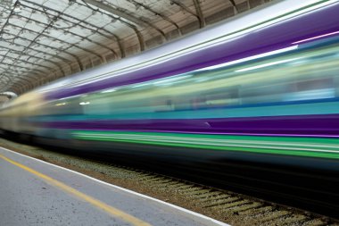 Tren. Modern yüksek hızlı tren istasyon platformunda hareket ediyor. Tren istasyonunun peronunda elektrikli tren var. Gün batımında demiryolu rayları. Demiryolu seyahat kavramı.