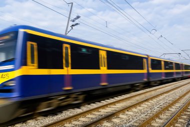 Tren. Modern yüksek hızlı tren istasyon platformunda hareket ediyor. Tren istasyonunun peronunda elektrikli tren var. Gün batımında demiryolu rayları. Demiryolu seyahat kavramı.