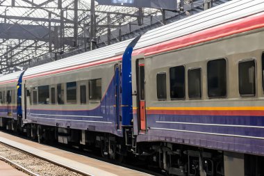 Tren. Modern yüksek hızlı tren istasyon platformunda hareket ediyor. Tren istasyonunun peronunda elektrikli tren var. Gün batımında demiryolu rayları. Demiryolu seyahat kavramı.