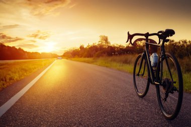 Motorsiklet. Bisiklet mi? Güzel bir gün batımında park edilmiş yol bisikleti, fotokopi alanı olan sıcak bir ışık. Güzel bir gün batımında park edilmiş bir motosiklet, sıcak bir ışık. Dünya Bisiklet Günü.