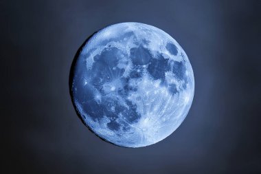 Blue Moon. Cold moon. Full moon. Super full moon. 15 December 2024. Super full moon with dark background. Moon. Supermoon. Blue super moon glowing with blue halo surrounded by small stars on black sky background.