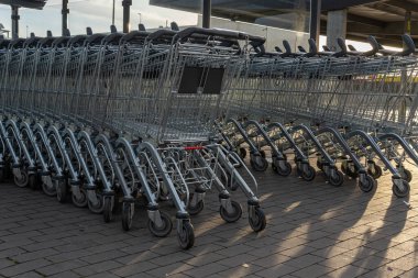 Otoparkta metal market arabaları, boş arabalar ve gün doğumunda insanlar. Kavramsal tüketici görüntüsü