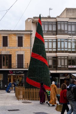 Manacor, İspanya; Aralık 01 2022: Merkezi bir meydanda dev bir Noel ağacı, İspanya 'nın Manacor kentindeki insanlar etrafta dolanıyor.