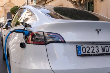 Felanitx, İspanya; 17 Mart 2023: Tesla şirketinin beyaz elektrikli arabası, elektrik şarj noktasında caddeye park edilmiş. Felanitx, Mallorca Adası, İspanya