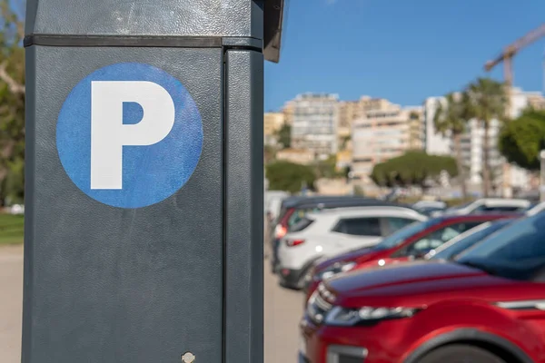 Close-up of vehicle parking symbol, with vehicles in the background out of focus