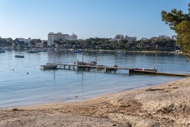 Portocolom sahilinin genel manzarası ve güneş doğarken geleneksel bir tekne iskelesi. Mallorca Adası, İspanya