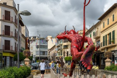 Manacor, Spain; april 30 2023: Manacor Encantat urban festival with large sculptures in the street of characters from folk tales or Rondalles. Sculpture of a devil giant running. Manacor, Spain clipart