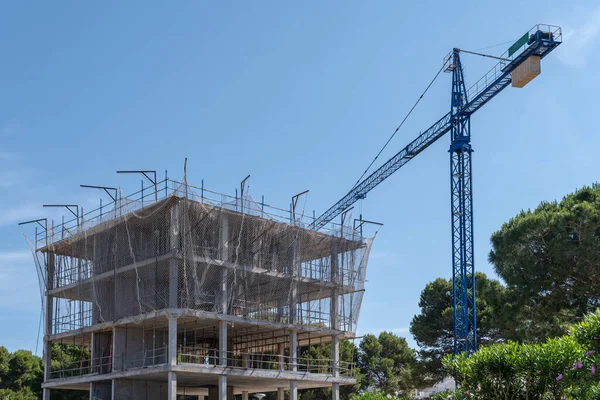 stock image Residential building under construction with an industrial crane. Cala Millor, island of Mallorca, Spain