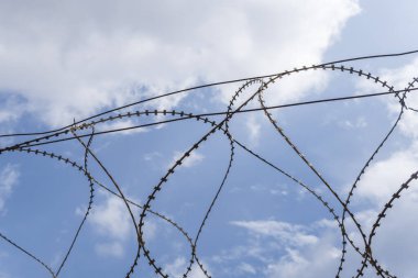 Mavi gökyüzünün arka planına karşı bir akordeon çitinin yakın çekimi. Özgürlüğün kavramsal görüntüsü