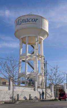 Manacor, İspanya; Ocak 02 2024: Şafak vakti, İspanya 'nın Manacor kentinde, şişeleri dolduran insanlarla dolu dev su tankı ve çeşmesi