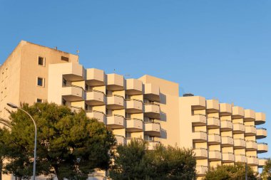 Günbatımında Majorcan 'ın Cala Millor kasabasında simetrik balkonlarla dolu bir otel kompleksinin ön cephesi.