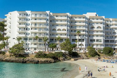 Cala Ferrera, İspanya; Mayıs 04 2024: Hamaklarla dolu ve otel kompleksleriyle çevrili ünlü Cala Ferrera plajının genel manzarası. Turist doygunluğunun görüntüsü. Mallorca Adası, İspanya