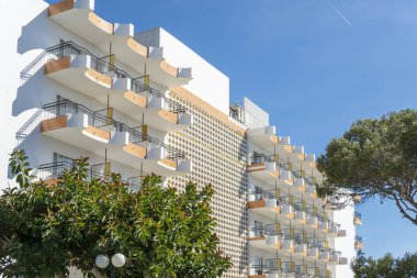 Cala d 'Or, İspanya; Mayıs 04: 2024: Güneşli bir sabahta Majorcan' ın Cala d 'Or kasabasında eski bir turist apartmanı binasının balkonları ile ön cephe