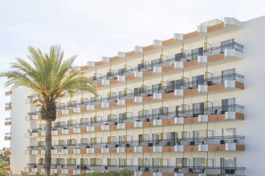 Cala d 'Or, İspanya; Mayıs 04: 2024: Güneşli bir sabahta Majorcan' ın Cala d 'Or kasabasında eski bir turist apartmanı binasının balkonları ile ön cephe