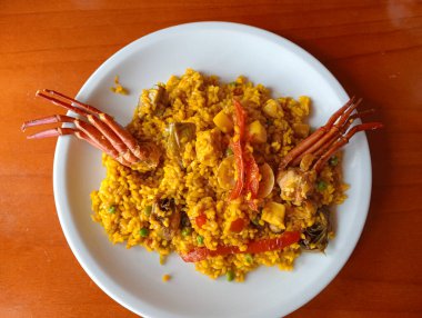 Geleneksel bir İspanyol yemeği olan deniz ürünleri paella tabağını ahşap bir masada yakın plan çek.
