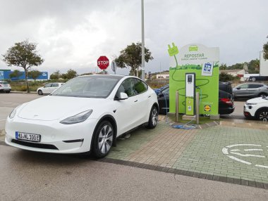 Felanitx, İspanya; 26 Ekim 2024: Beyaz Tesla elektrikli araba bir elektrik şarj istasyonunda park edilmiş ve şarj ediliyor