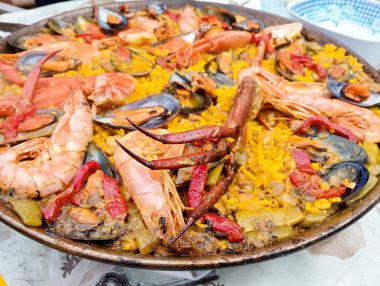 Masadaki paella tavasındaki deniz ürünleri paella 'sının yakın çekimi. İspanyol gastronomisinin resmi