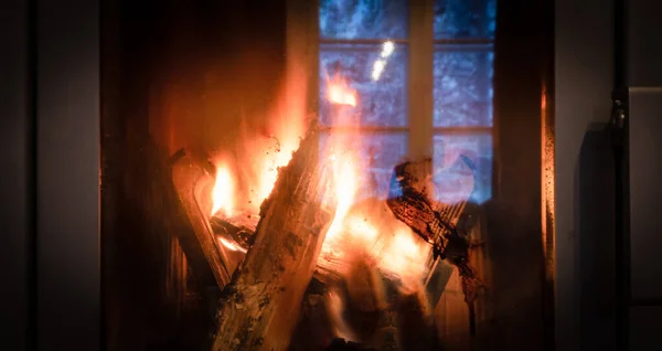 Fire in the fireplace behind a closed glass door. Selective focus. Shallow depth of field.